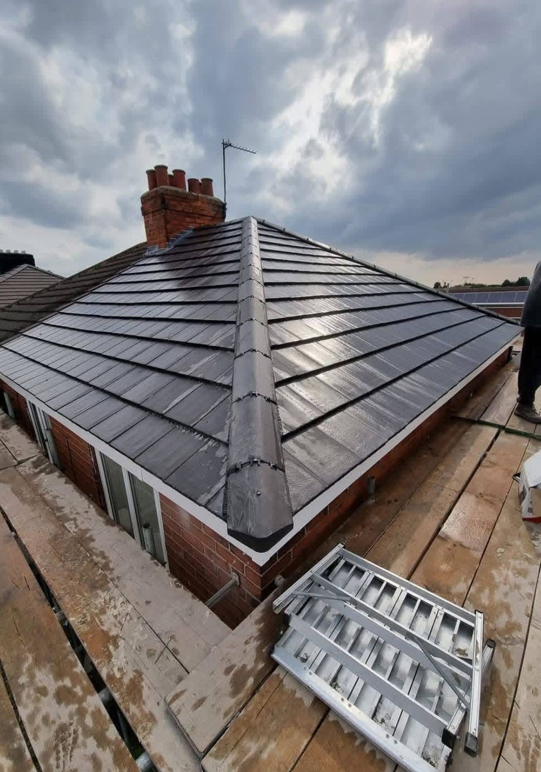 Completed hipped roof re-tile in grey concrete tiles with new ridge and hip pointing