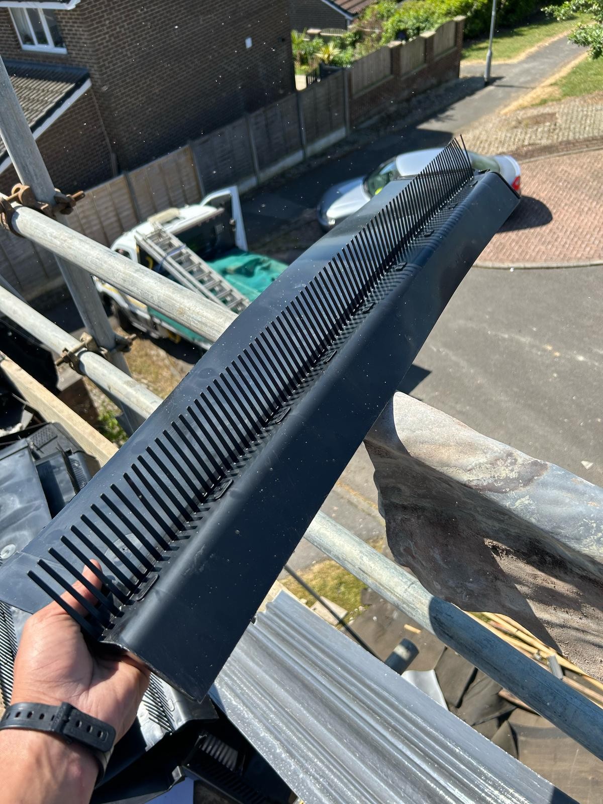 Black dry verge unit held up before being fixed to a new tiled roof edge