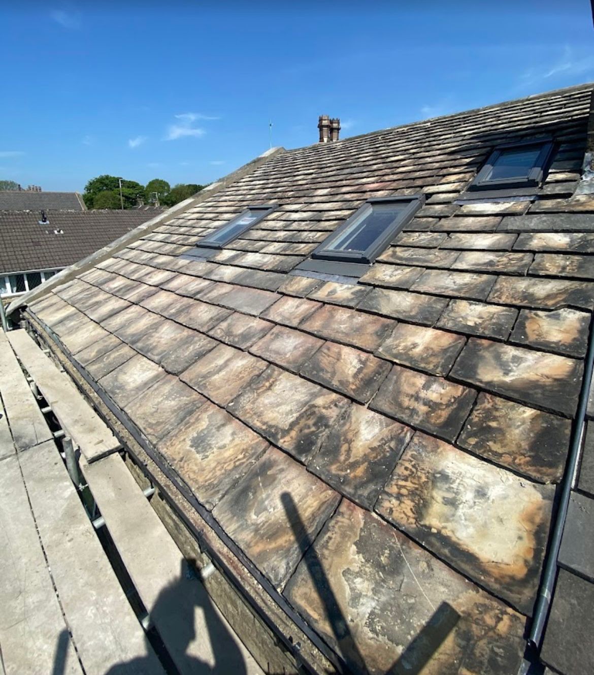 Old stone slate roof with Velux windows showing slipped and worn slates