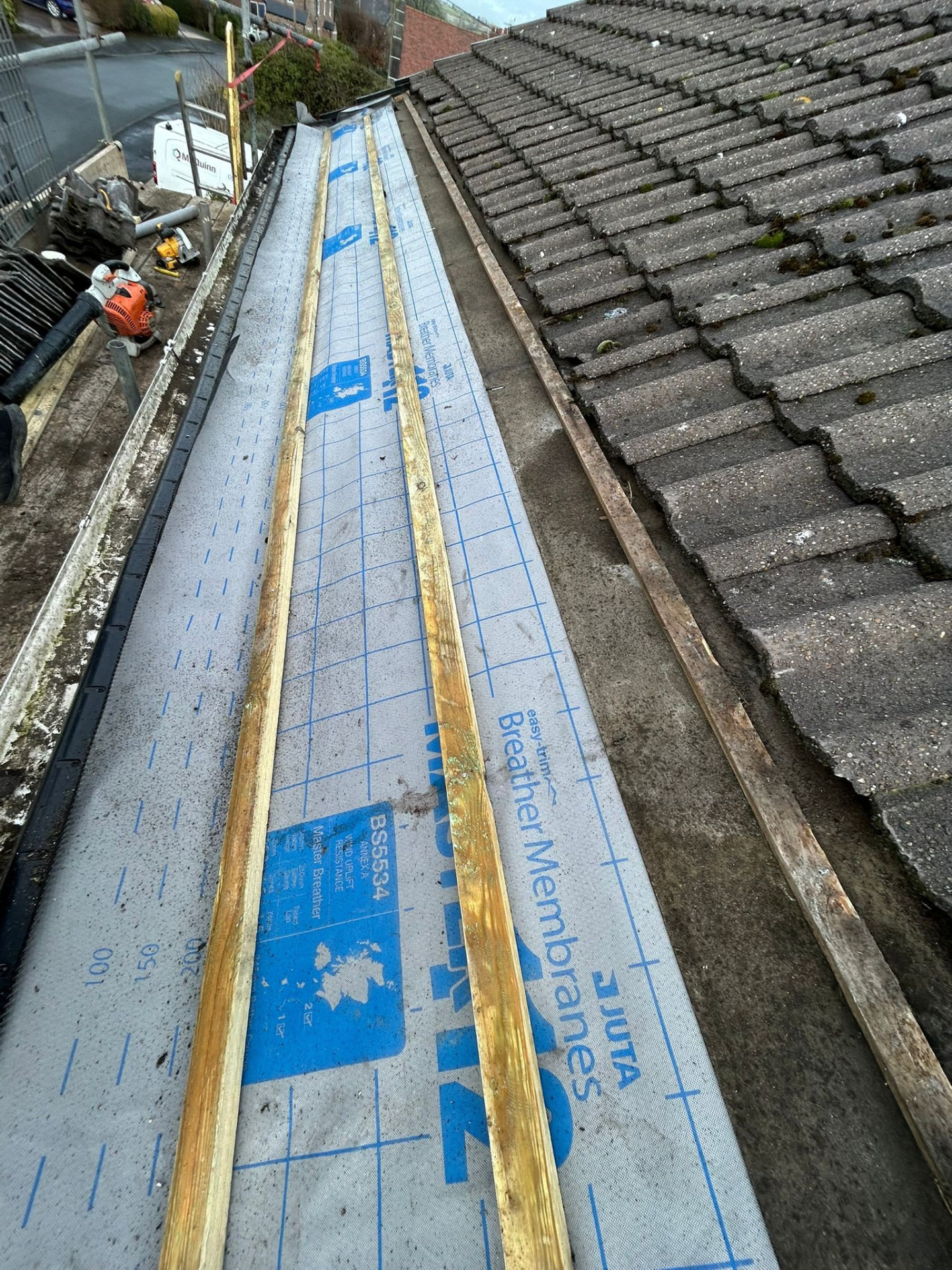 Tiles being loaded and set out across a battened roof slope