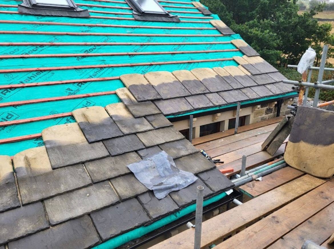 Stone slates being re-laid over new membrane on a Yorkshire roof