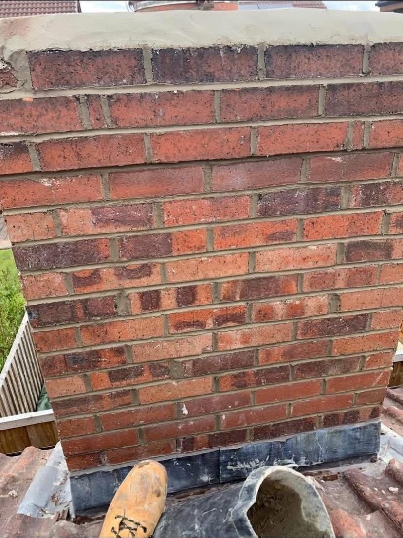 Freshly repointed chimney brickwork with new lead flashing dressed into the roof