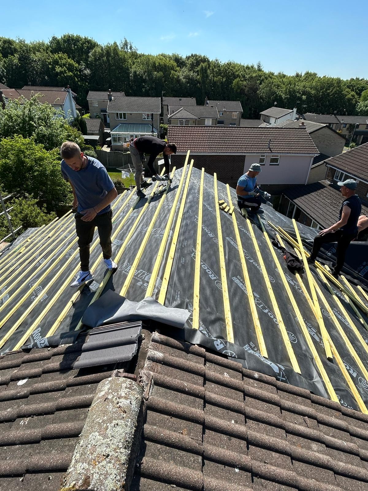 Roofers loading tiles onto freshly battened roof slopes during a re-roof
